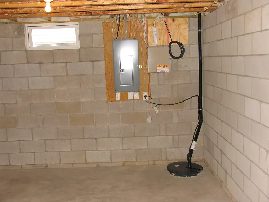 Sump pump in a pit next to a block foundation wall
